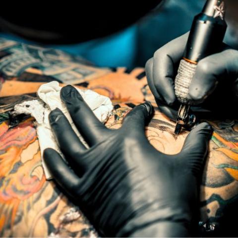 A photo of a tattoo artist applying ink to skin.