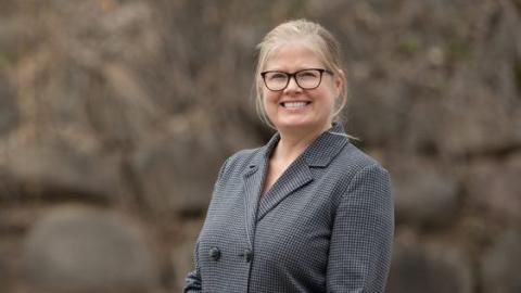 Photo of Professor Megan Moreno in grey suit jacket and glasses, outdoors, smiling at the camera.