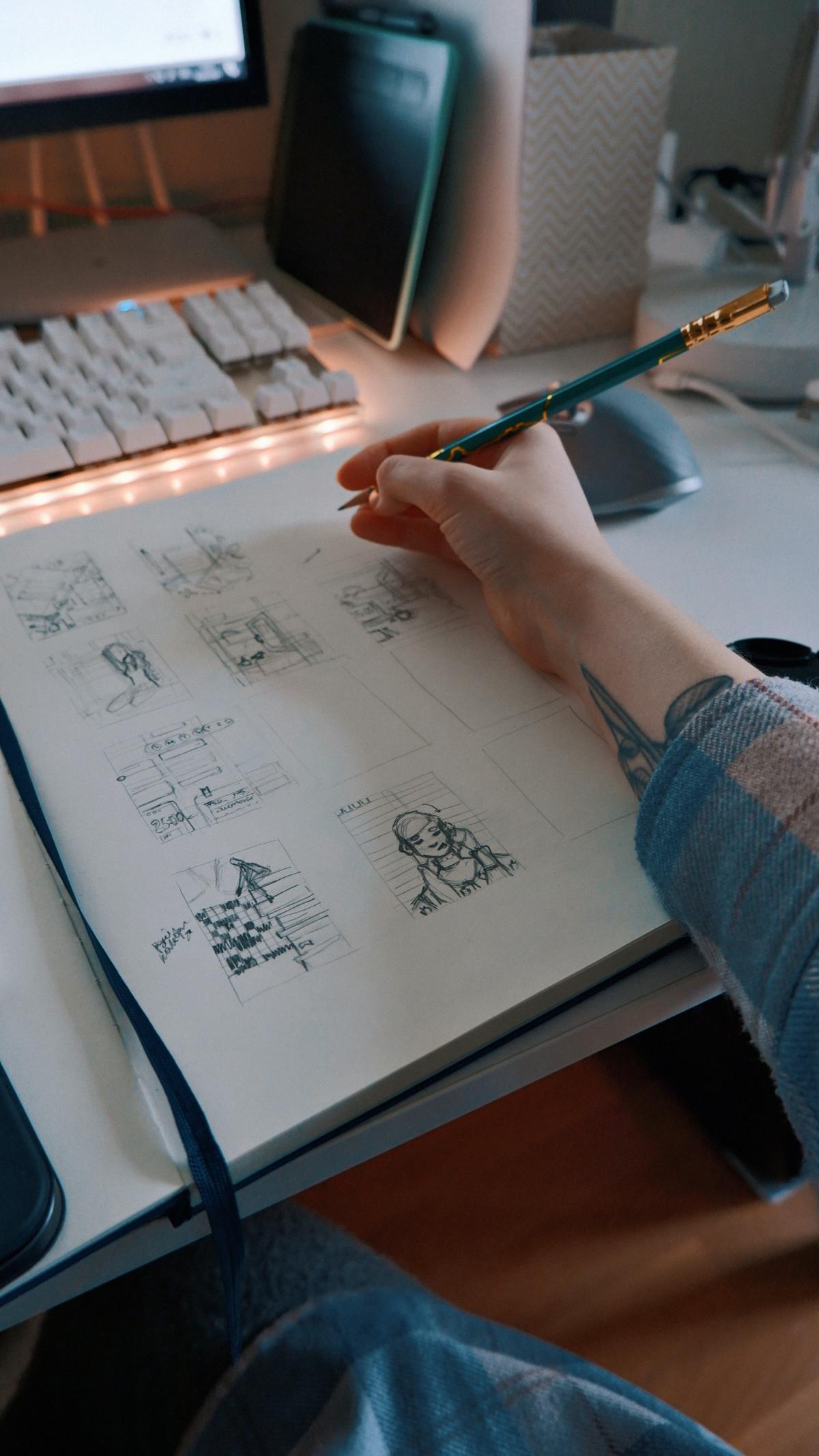 A person sitting at a desk with a pencil, drawing.