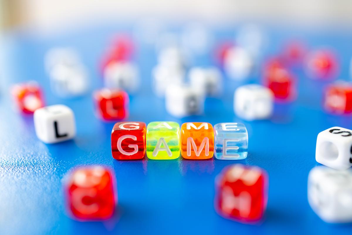 Colorful dice spread out on a blue background, in the center the dice spell GAME.