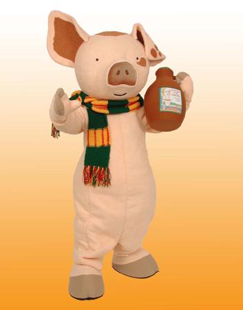 Book character Pancake Pig is dressed in a green and gold scarf and holding a jug of syrup.