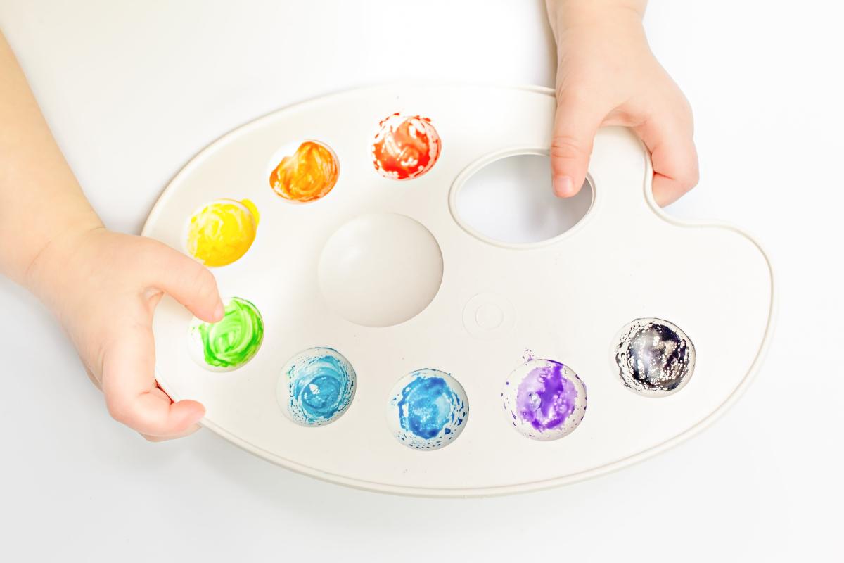 A paint palette is held by a child.