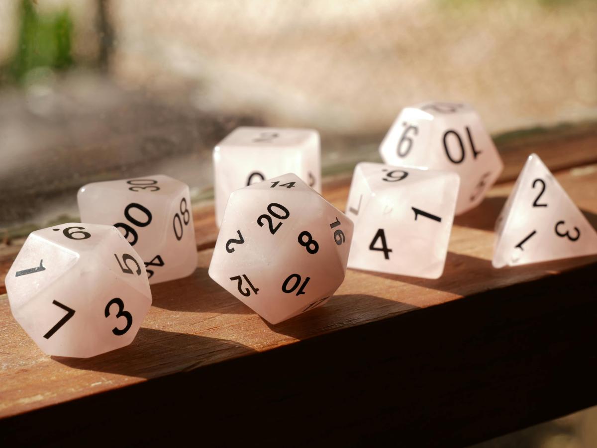 Set of white dice used for role playing games on a wooden tabletop.  